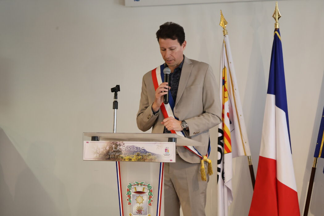 e maire Yves Palmieri prononce un discours au pupitre lors d’une cérémonie d’investiture, portant une écharpe tricolore devant des drapeaux officiels.