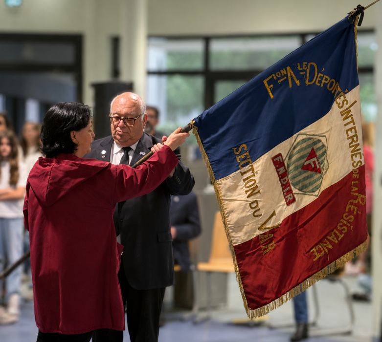Lors de la cérémonie de transmission du drapeau Unadif au collège André-Malraux de La Farlède, un homme remet le drapeau tricolore de l’association à la principale de l’établissement.