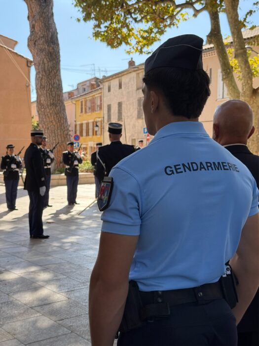Prise de commandement de la brigade de gendarmerie de La Farlède. Des gendarmes en tenue de cérémonie, alignés avec fusils et képis, sur la place pavée devant la mairie."
