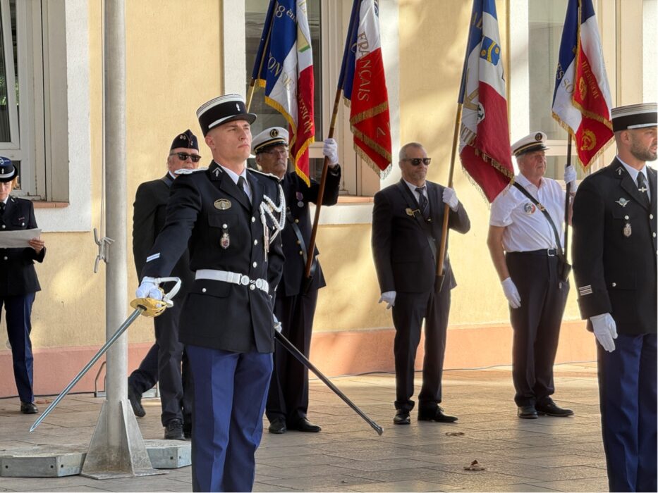 Prise de commandement de la brigade de gendarmerie de La Farlède. Des militaires en tenue de cérémonie, gants blancs et drapeaux, dont un officier au sabre, alignés devant la mairie.